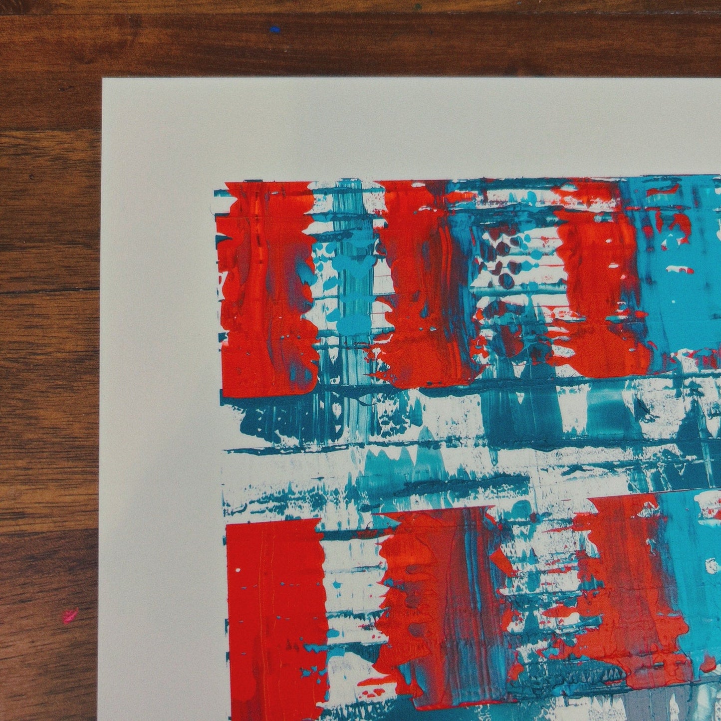 Abstract art print with red, blue, and white abstract patterns on a wooden surface.